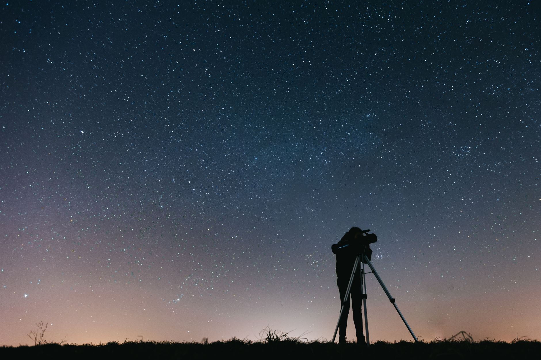 Une personne observe le ciel étoilé avec un télescope