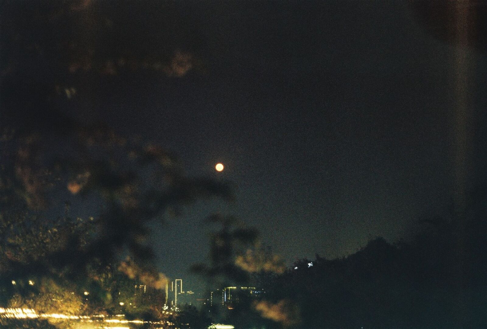 Lune visible au-dessus d’un horizon urbain nocturne
